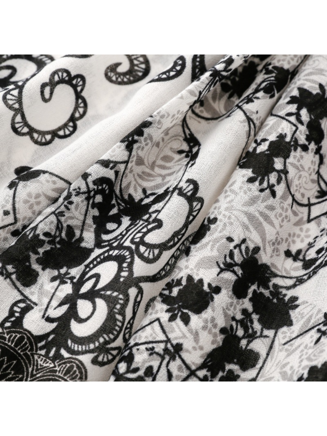Close-up of floral motifs and curling outlines across diagonal scarf folds