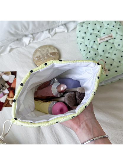 Open Cream cosmetic pouch showing white interior lining with staged cosmetic containers and brushes