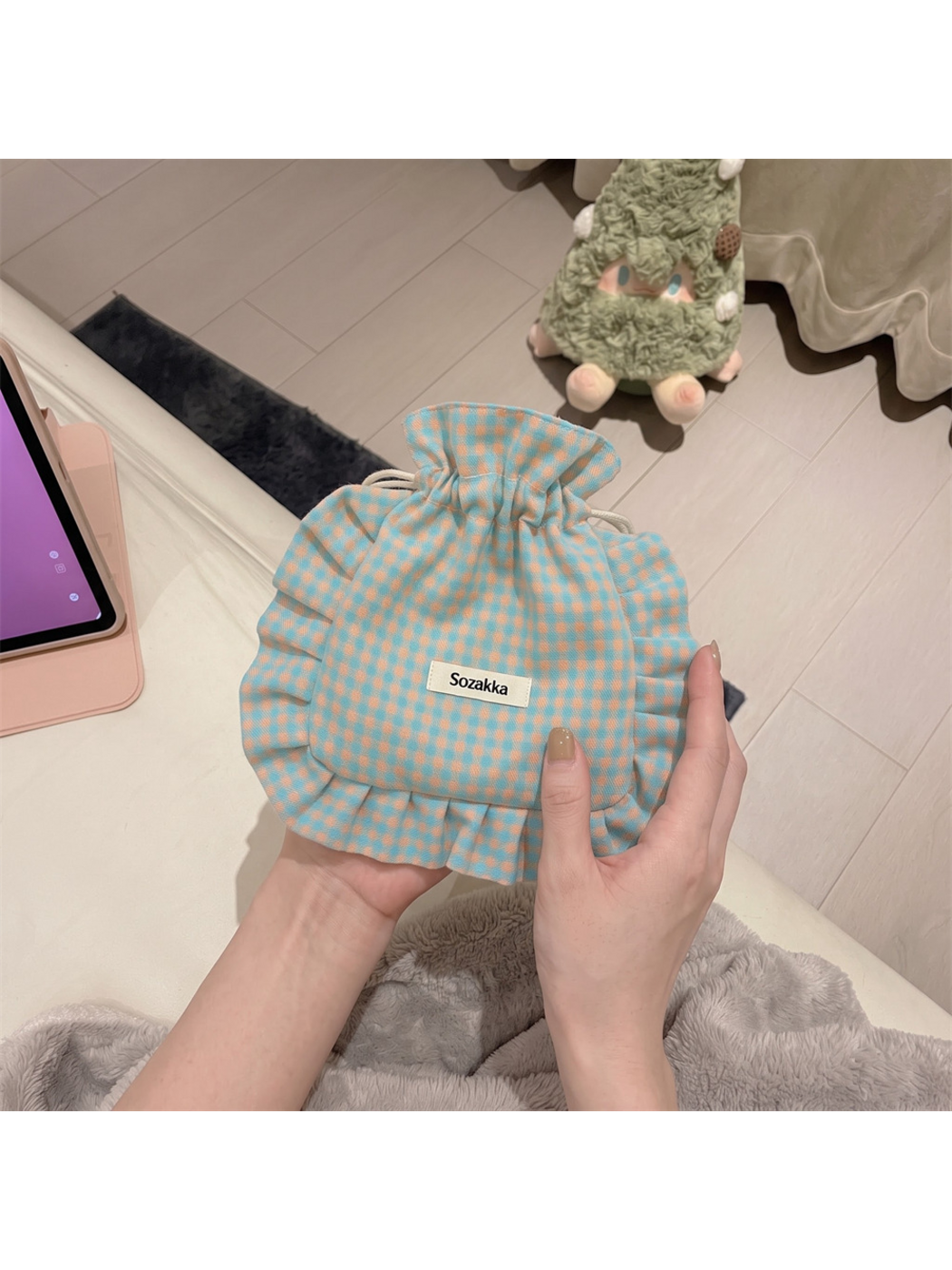 Checked drawstring pouch held upright, showing its rounded front and ruffled border
