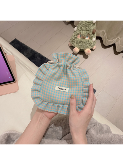 Checked drawstring pouch held upright, showing its rounded front and ruffled border