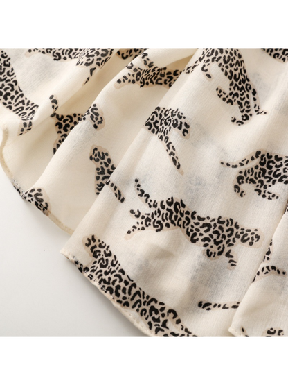 Close-up of leopard silhouettes beside the finished edge of a pale scarf