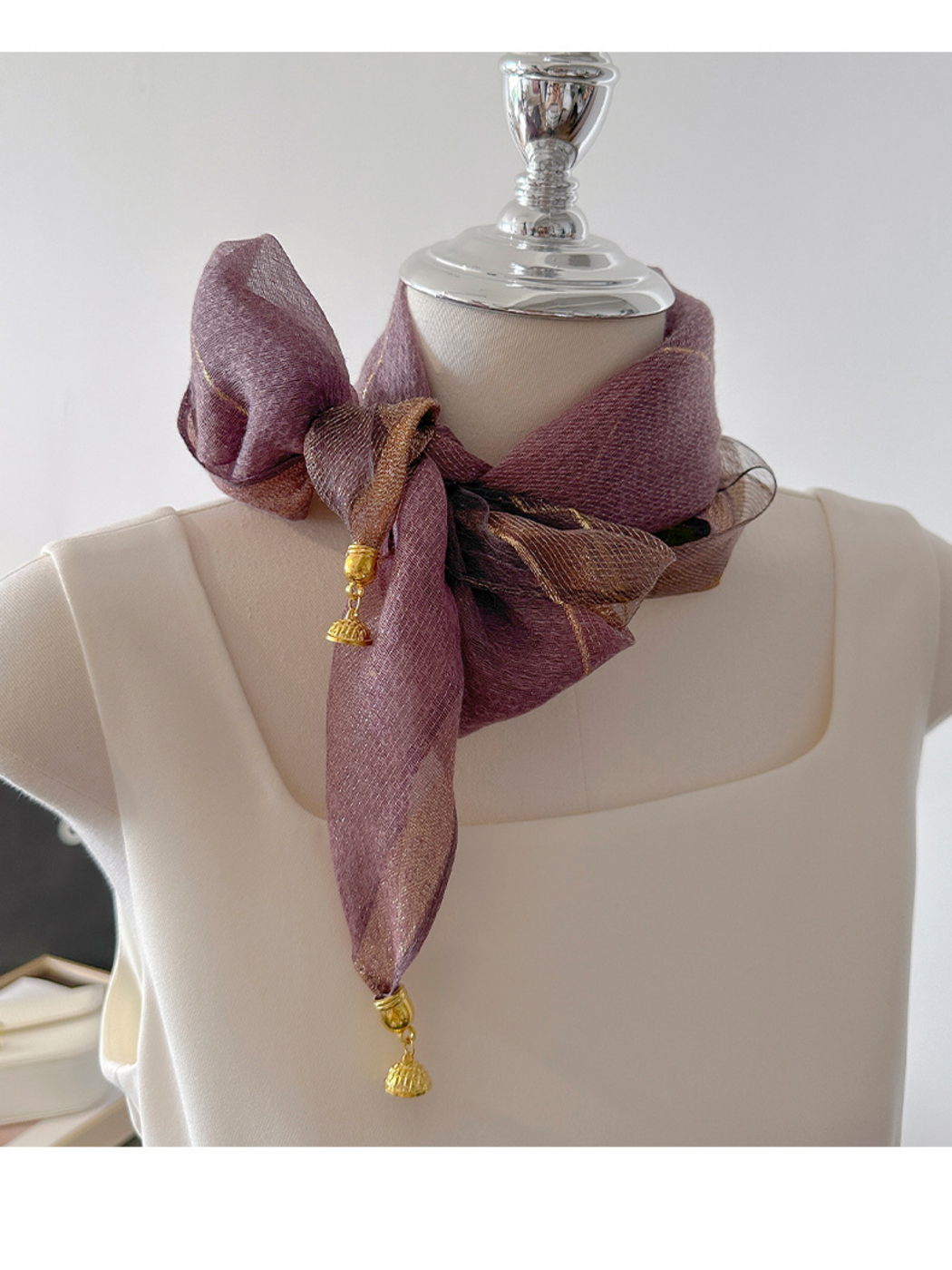 Purple scarf tied in a side bow with hanging gold-tone end ornaments