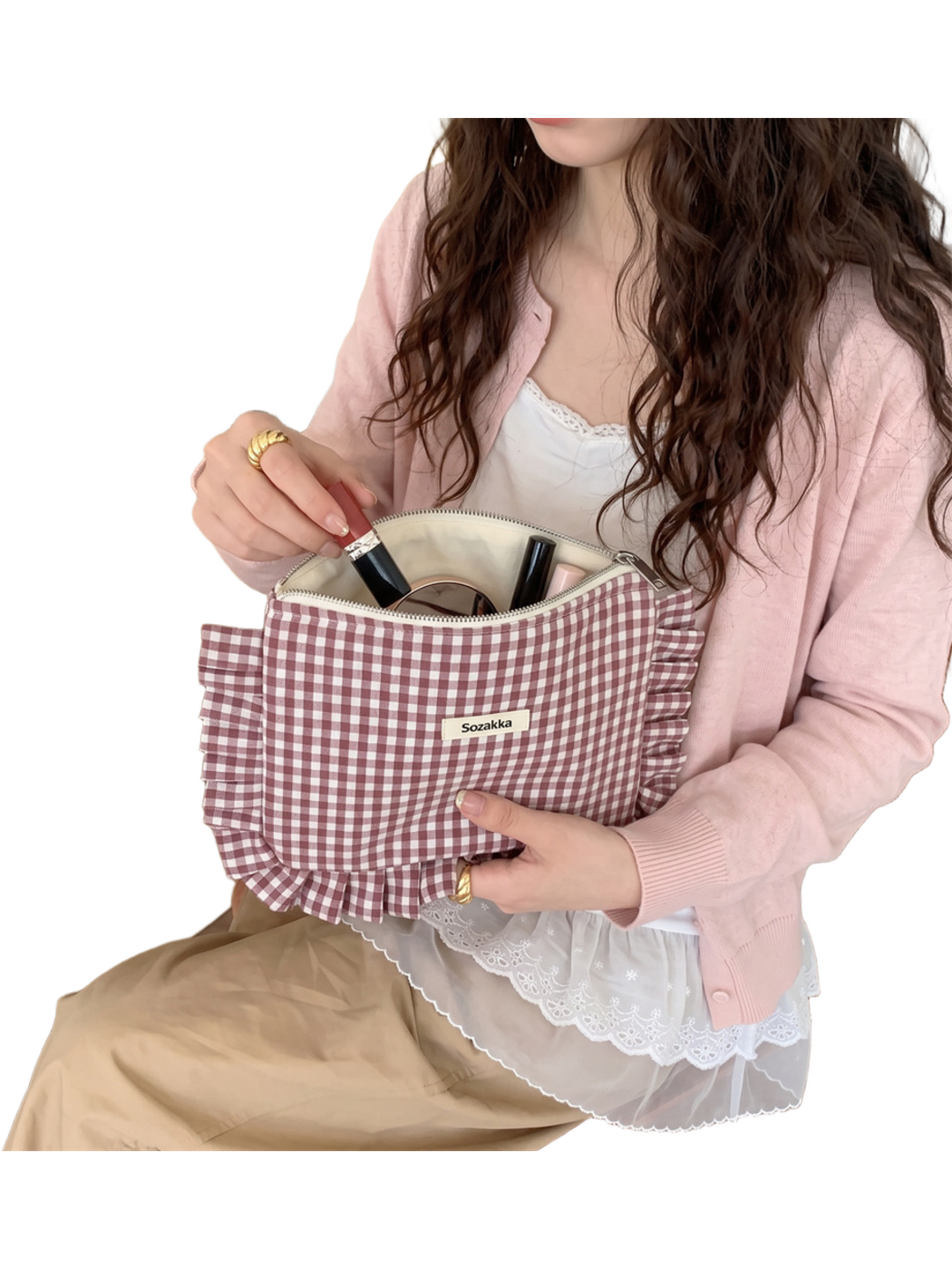 Burgundy gingham cosmetic pouch held open with cosmetics visible inside