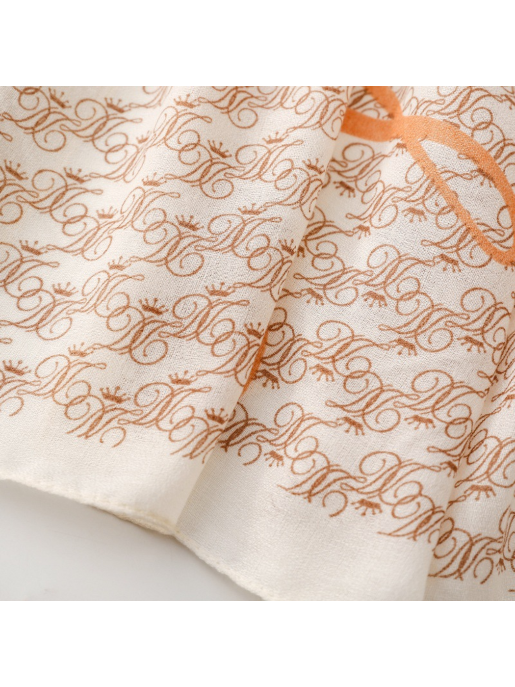 Close-up of the ivory scarf border and narrow finished edge beneath brown ornate motifs