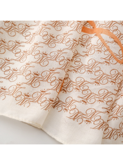 Close-up of the ivory scarf border and narrow finished edge beneath brown ornate motifs