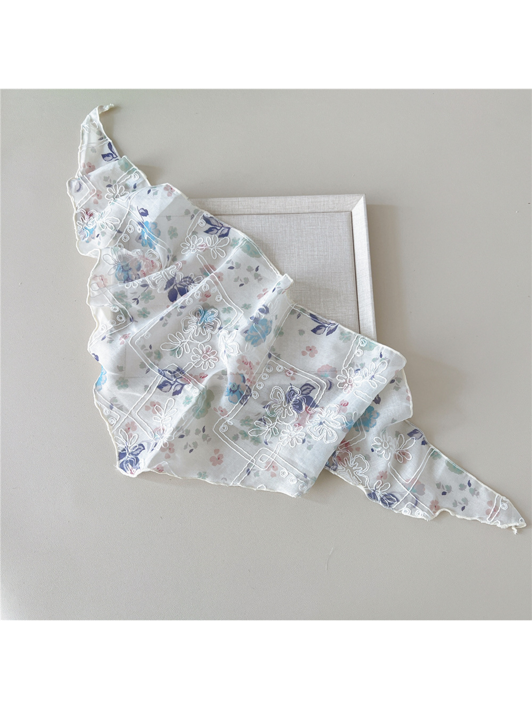 Floral scarf with white embroidery draped diagonally with both ends extended