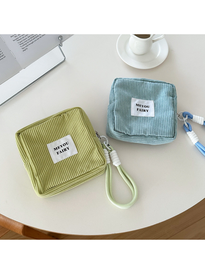 Green and Blue ribbed makeup bags showing bordered front panels and wrist-loop attachments