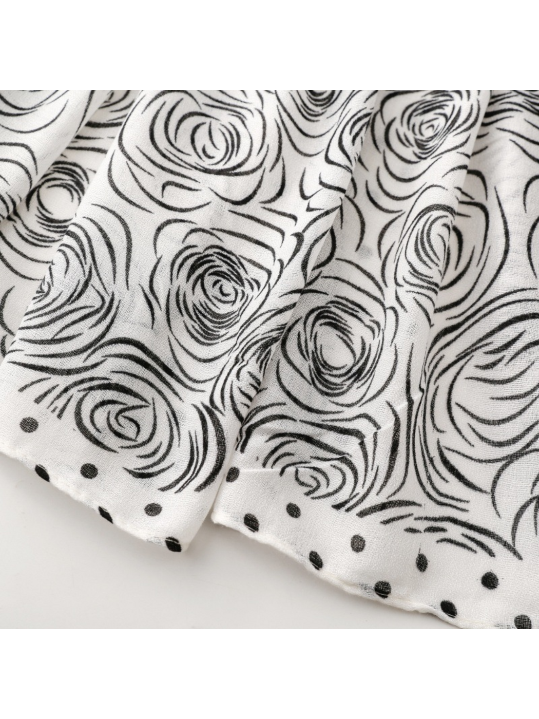 Close-up of black rose motifs beside the scarf's dotted border