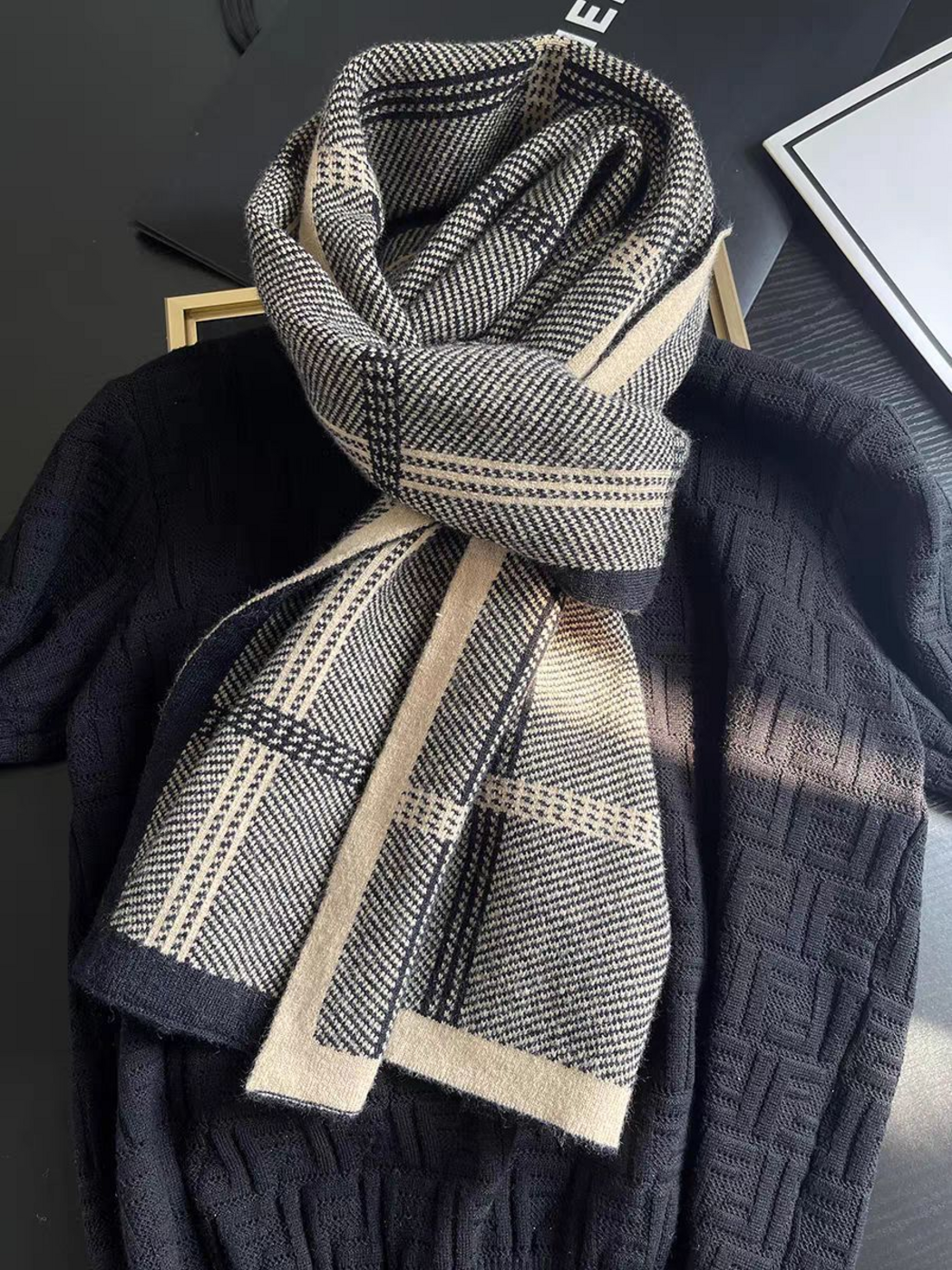 Black plaid scarf knotted over a dark sweater, showing contrasting border faces