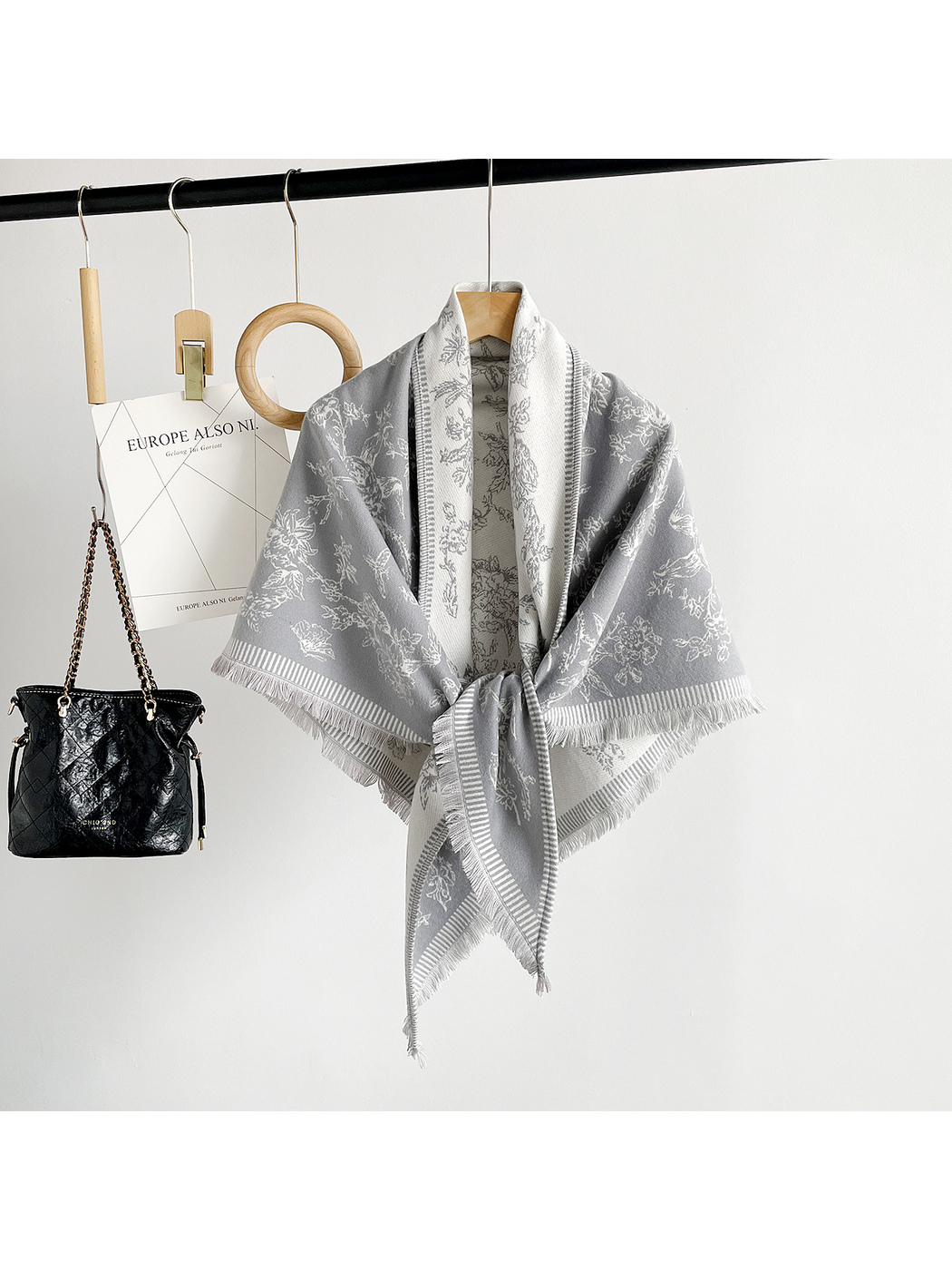 Gray floral scarf tied at the front on a wooden hanger