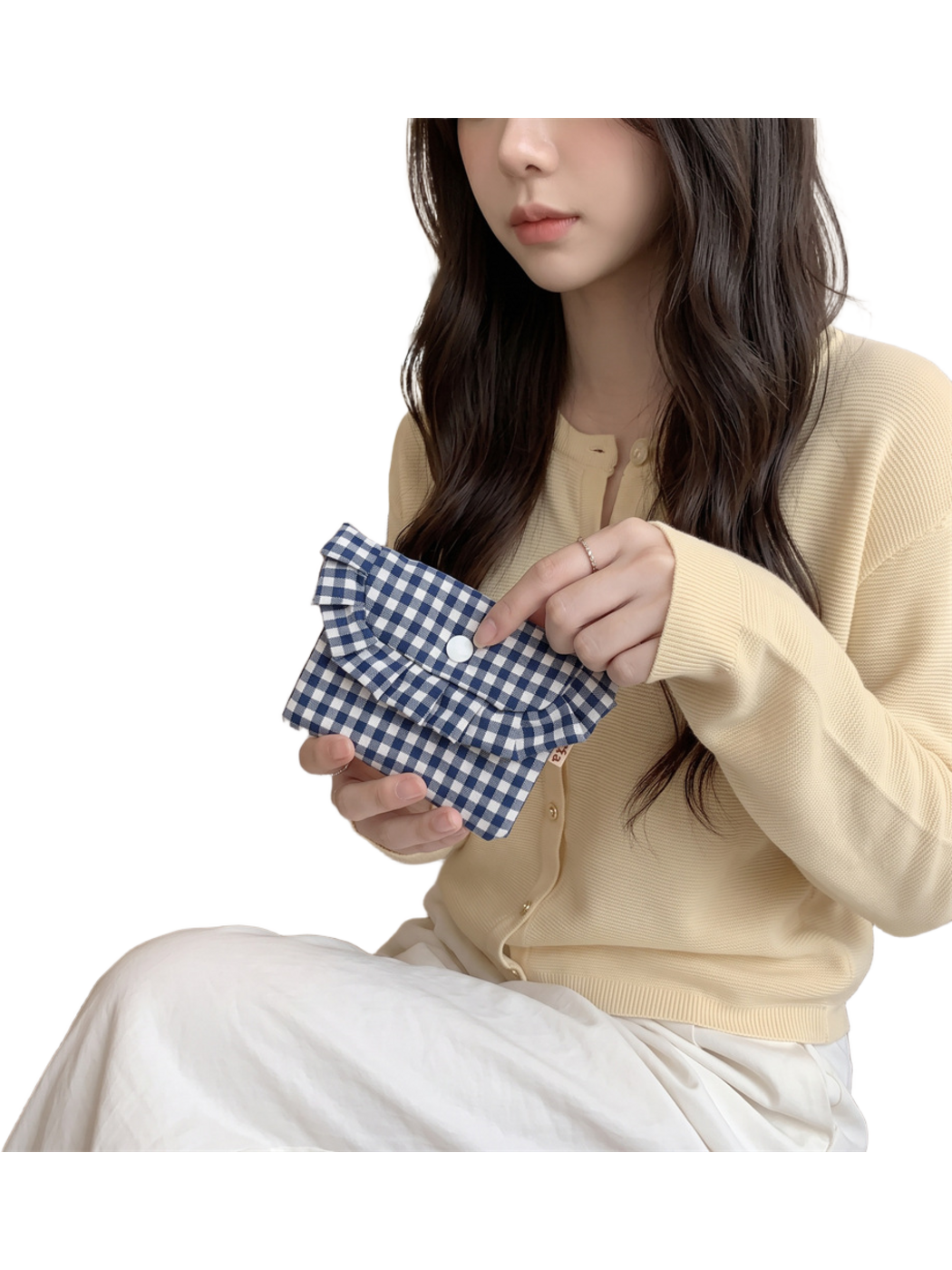 Navy gingham coin purse held at an angle with a finger beside the white snap