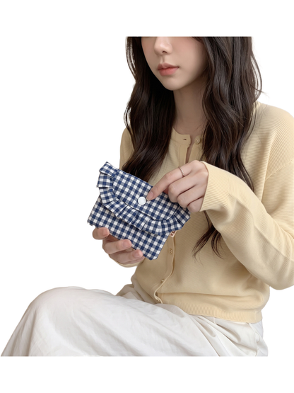 Navy gingham coin purse held at an angle with a finger beside the white snap