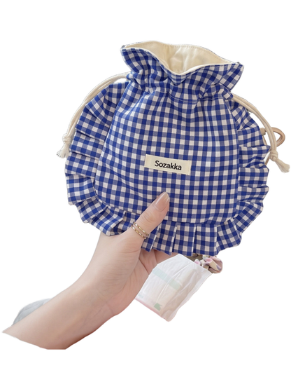 Gingham drawstring pouch held on a train with its opening spread