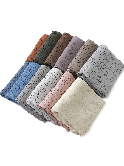 Folded scarves in several colors arranged diagonally on a white background