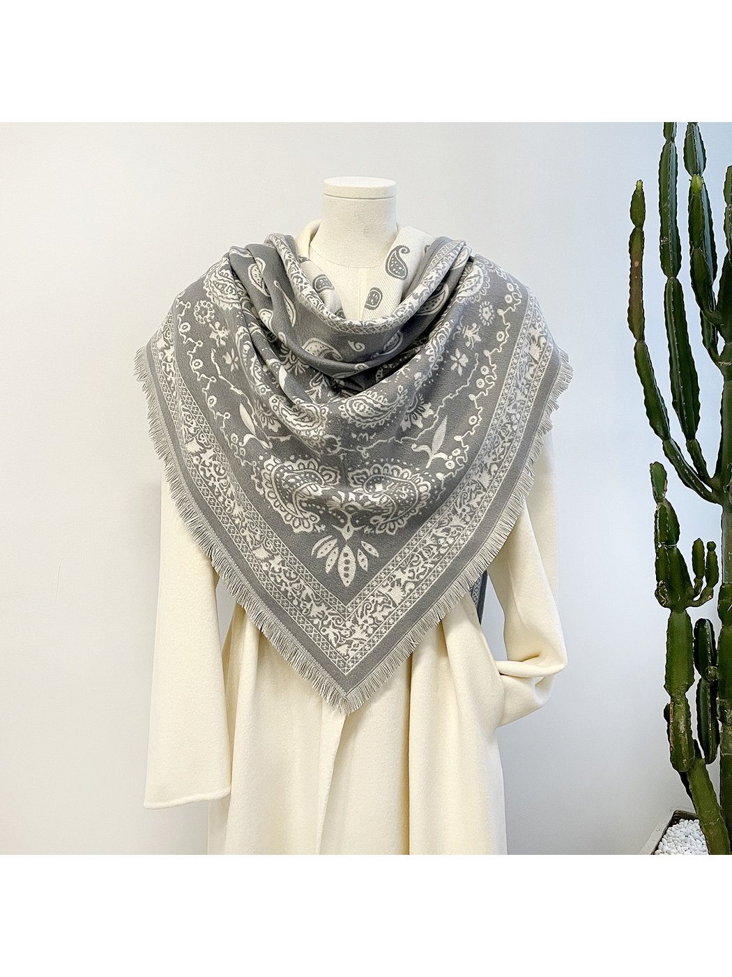 Red paisley scarf looped on a hanger with contrasting ivory reverse and fringed triangular points