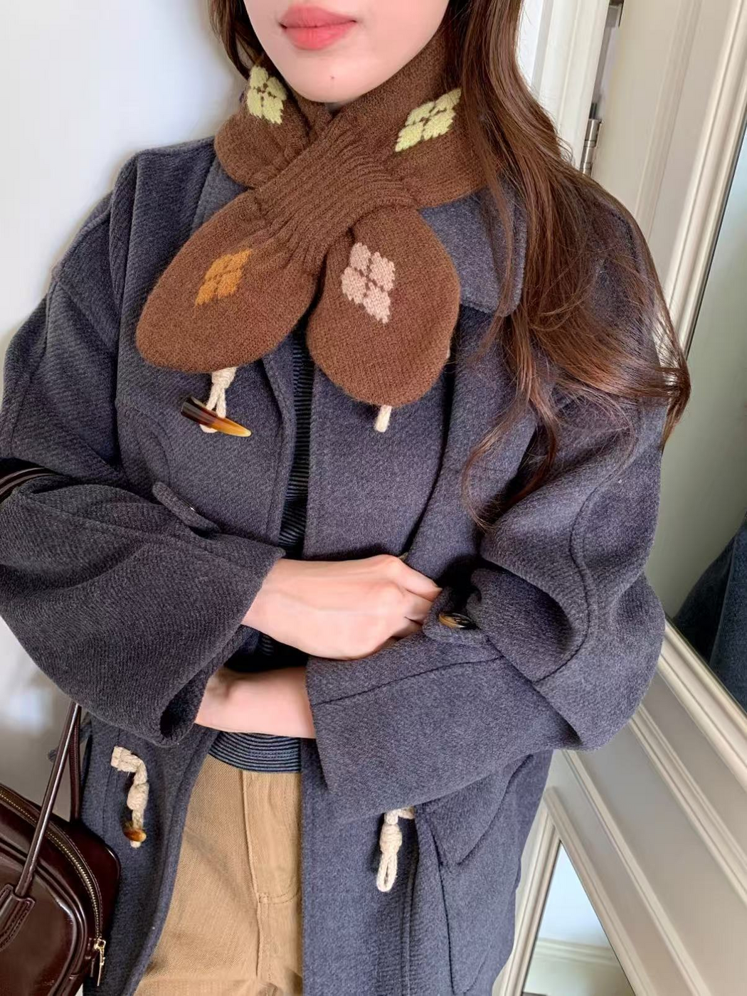 Close-up of Brown scarf worn over a dark coat, showing fuzzy knit texture and the ribbed loop