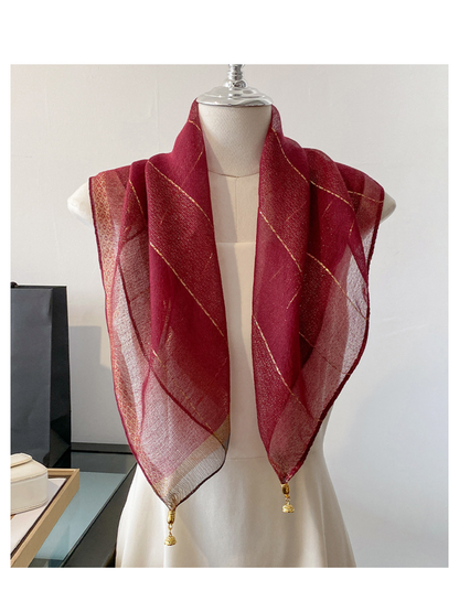 Burgundy scarf draped on a mannequin with metallic-look lines and gold-tone end ornaments
