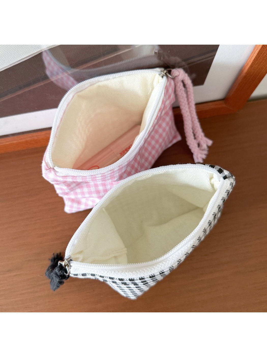 Pink Gingham and Black makeup bags open to show their cream-colored linings