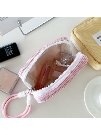 Pink makeup bag shown open with a pale interior and cosmetics inside
