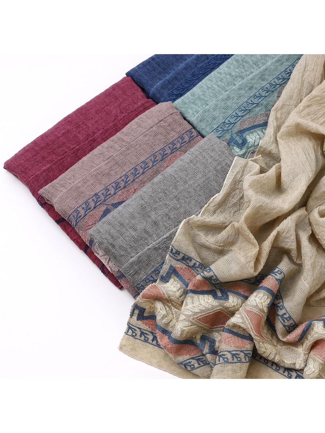 Close-up of folded scarf colors with a draped geometric and leafy border in the foreground