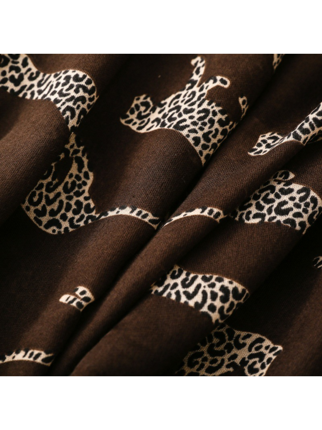 Close-up of spotted leopard silhouettes across brown scarf folds
