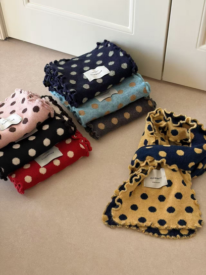 Yellow scarf loosely looped to show its navy reverse beside folded polka dot scarves