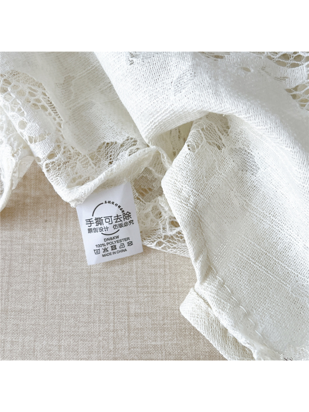 Close-up of White floral lace, fine textile texture and an attached cloth label