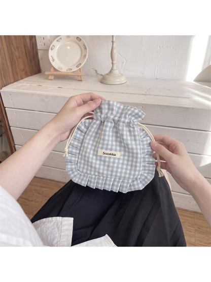 Gray gingham drawstring pouch held upright by its top edge and cord