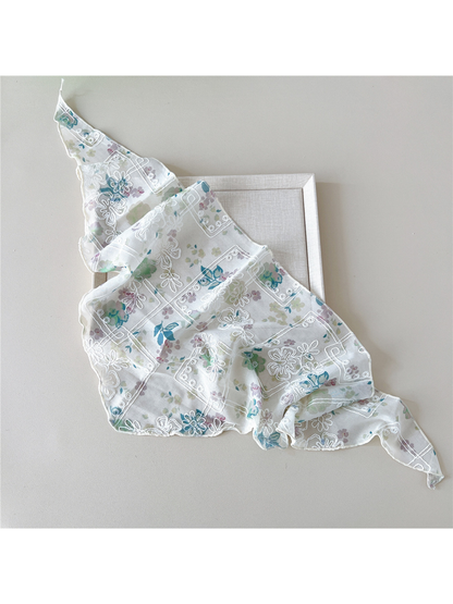 Floral scarf with white embroidery loosely spread diagonally over a tray