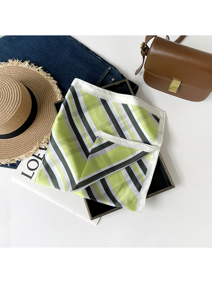 Green striped scarf loosely folded over a black tray