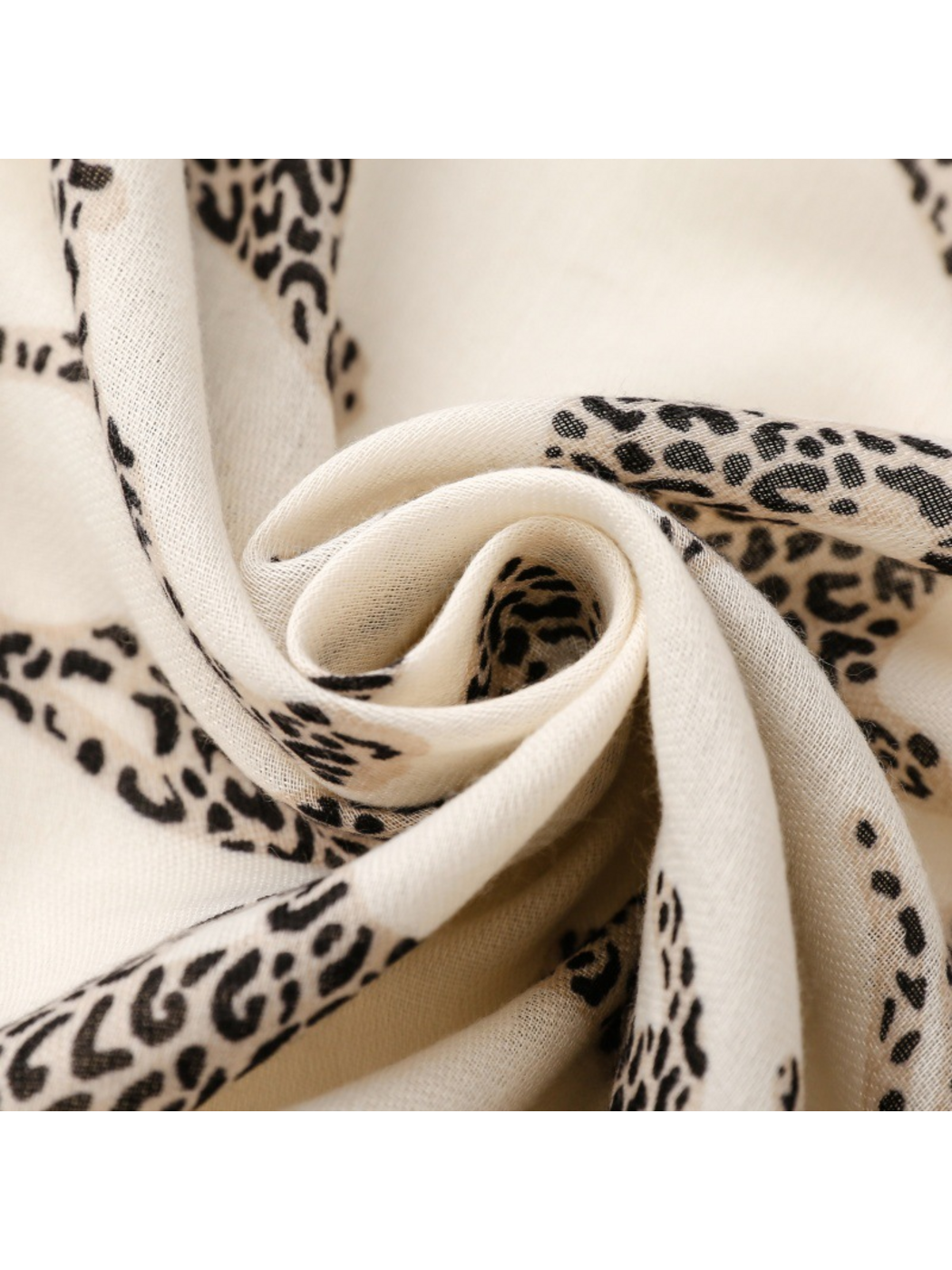 Close-up of a pale leopard-motif scarf arranged in a spiral fold