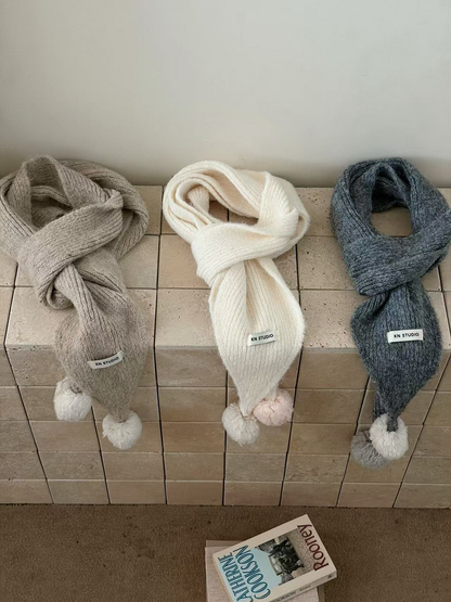 Beige, White and Gray scarves arranged in loops with tapered ends and contrasting pom-poms