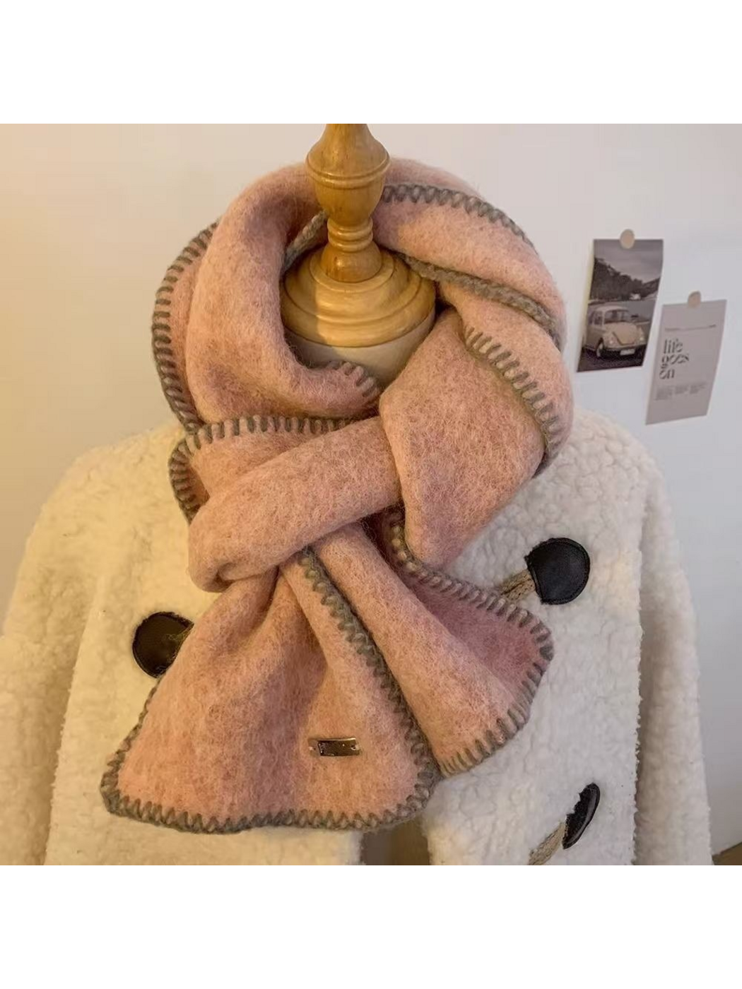 Pink scarf looped around a mannequin with gray stitched edges and hanging ends