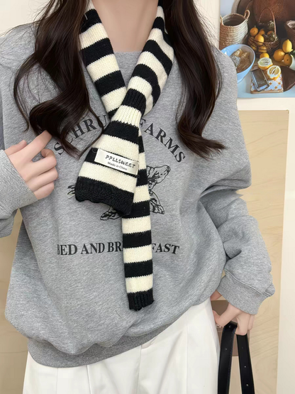Black striped knit scarf looped over a gray sweatshirt