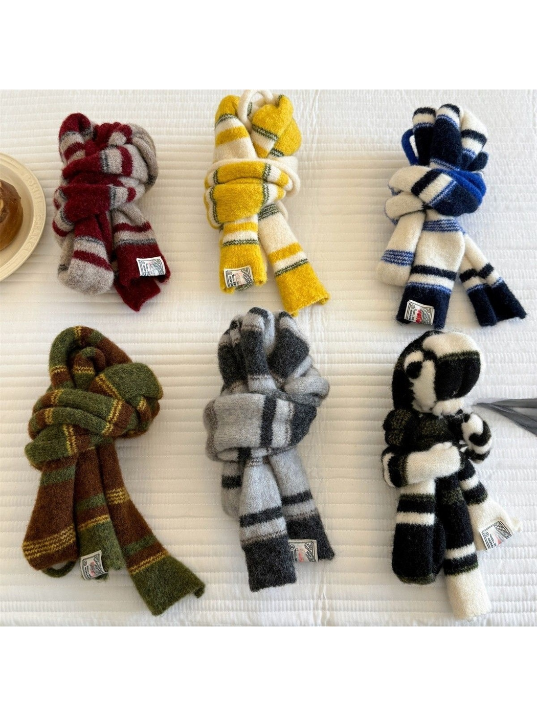 Six striped scarf colors folded into compact knots on a white surface