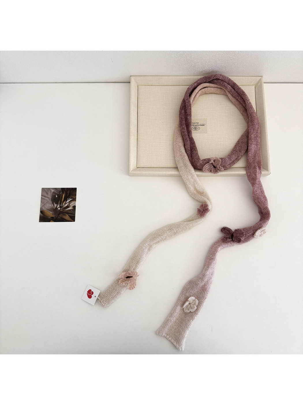 Brown gradient knit scarf laid in a loop with cream sections and raised embellishments