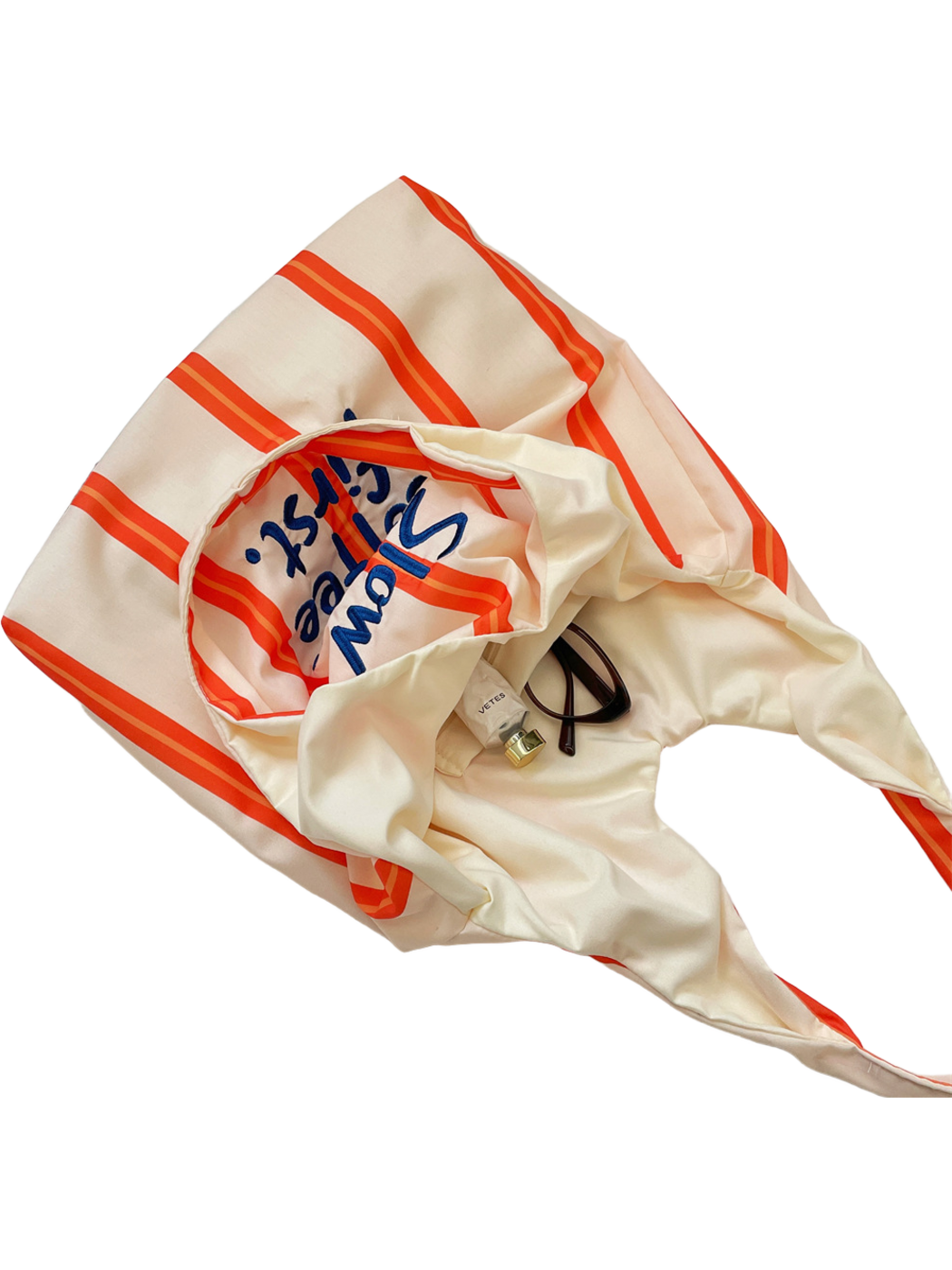 Orange tote bag opened to show its cream-colored interior, cropped detail