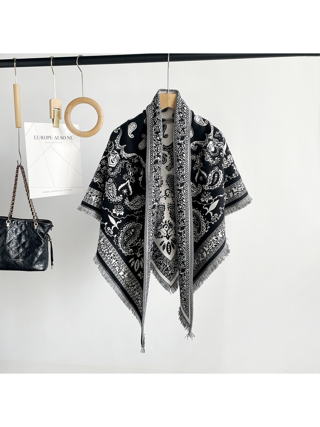 Brown paisley scarf draped on a hanger with ornamental borders and fringed points