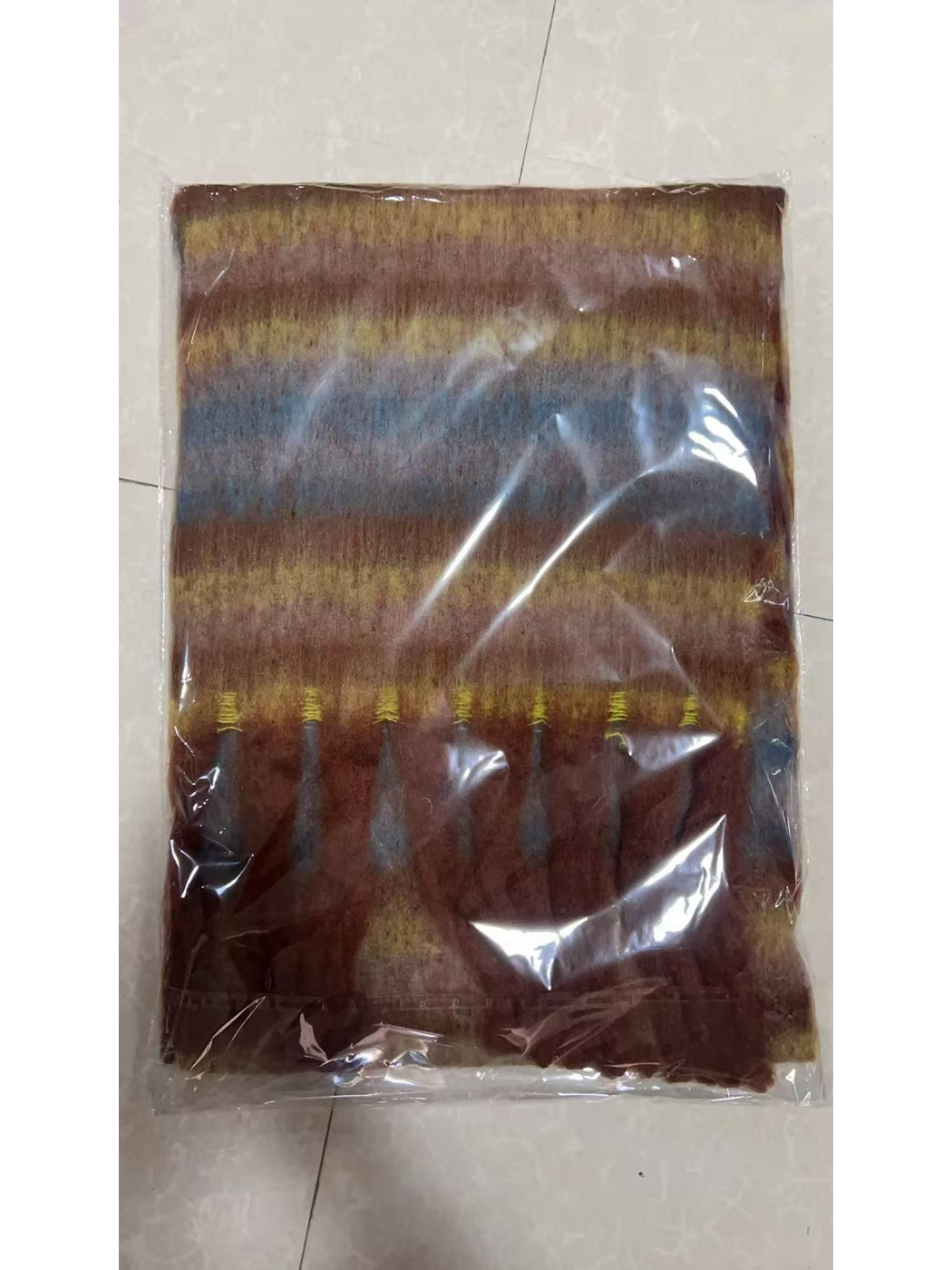 Caramel striped scarf folded inside clear plastic packaging