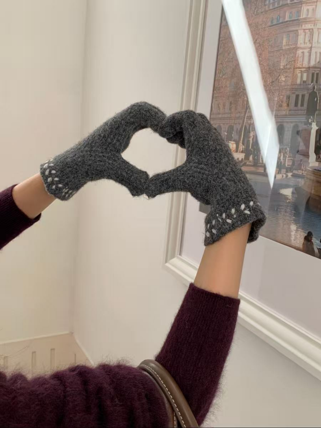 Gloved hands forming a heart, showing embroidered cuffs