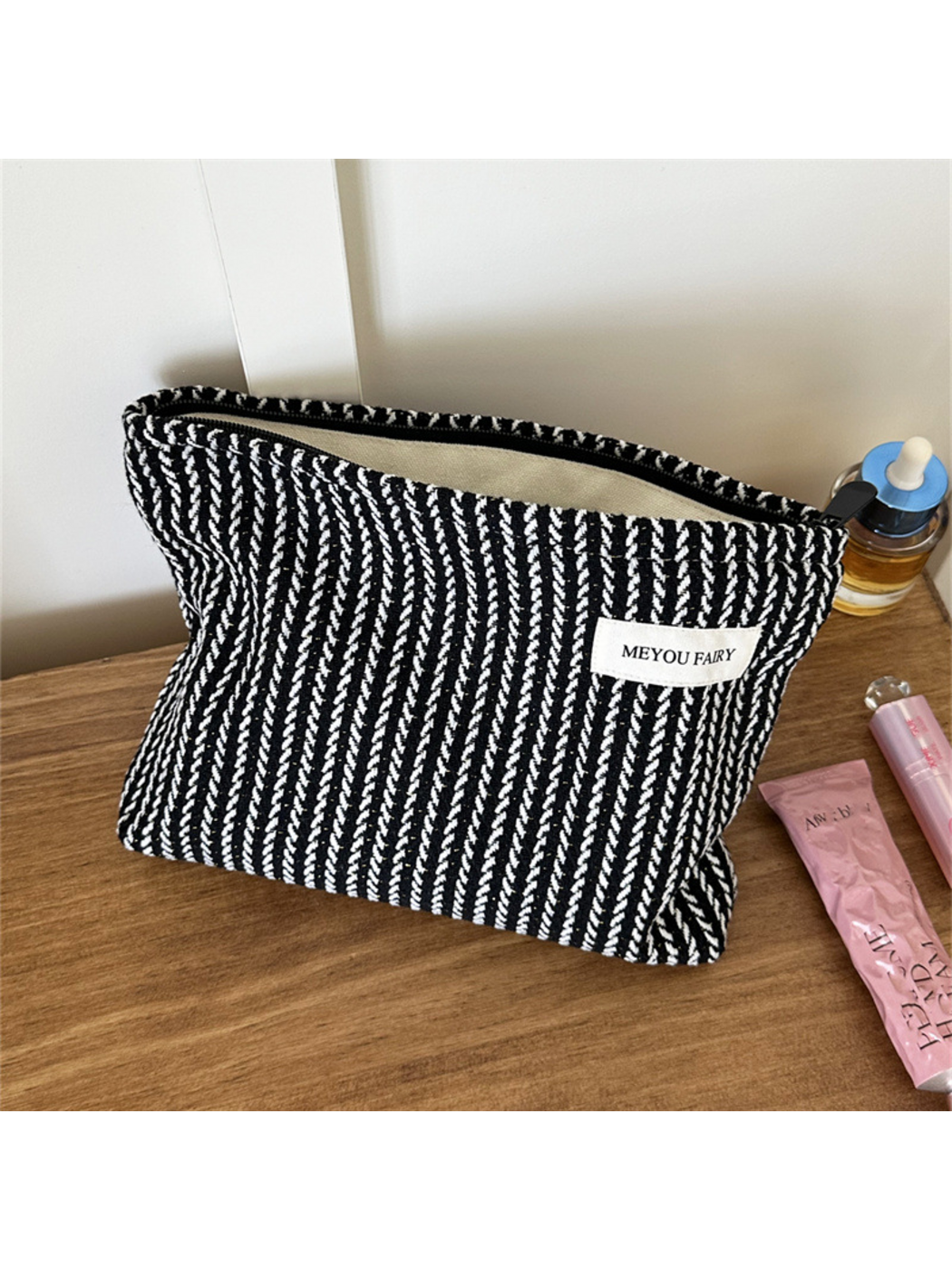 Black makeup pouch with contrasting white textured stripes, upright with pale lining visible