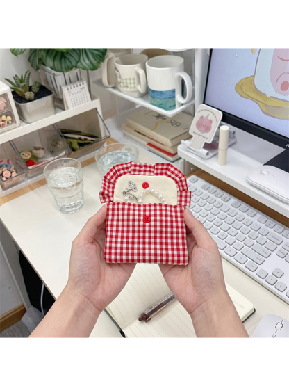 Red gingham coin purse held open, showing the light interior and both snap components