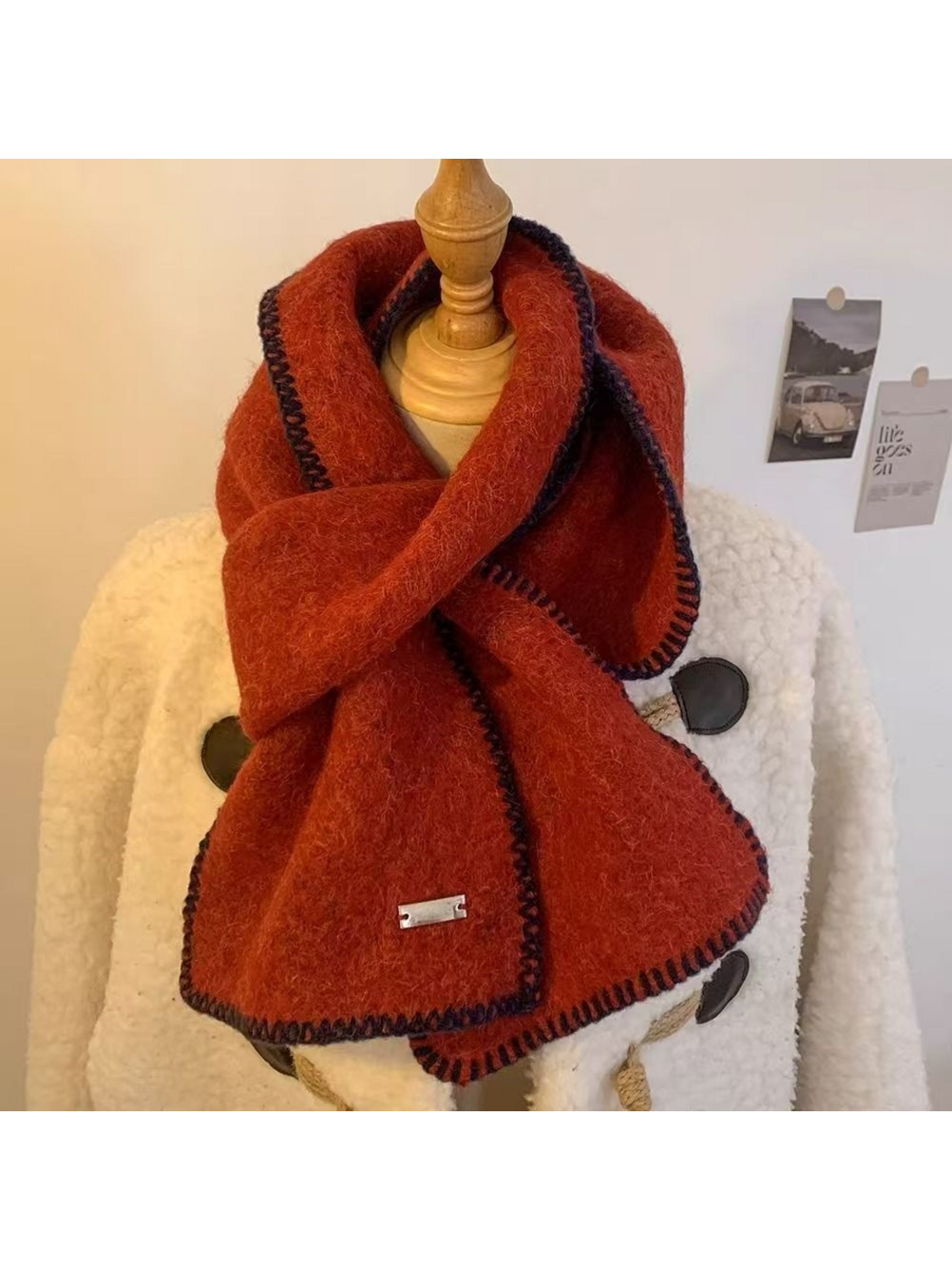 Red scarf looped around a mannequin with dark blanket-stitched edges