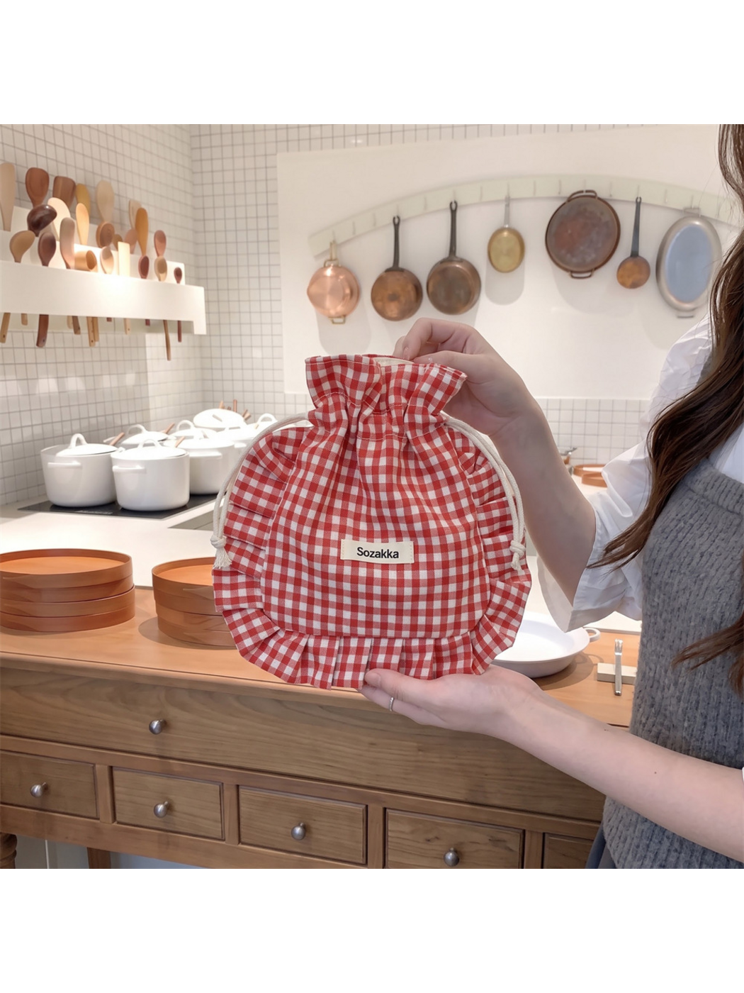 Red gingham drawstring pouch held upright with cream cords visible on both sides