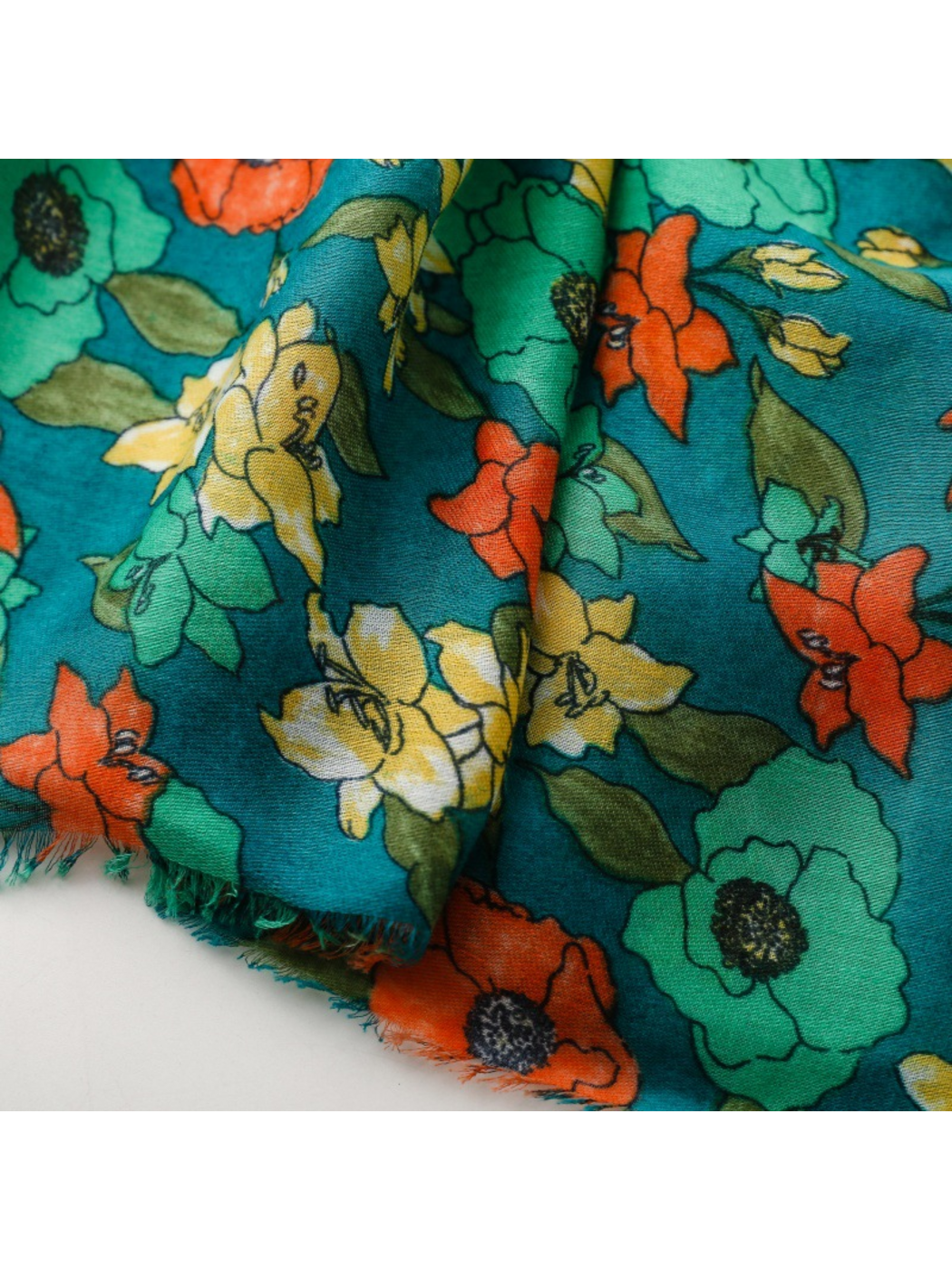Close-up of teal floral scarf folds and fringed edges