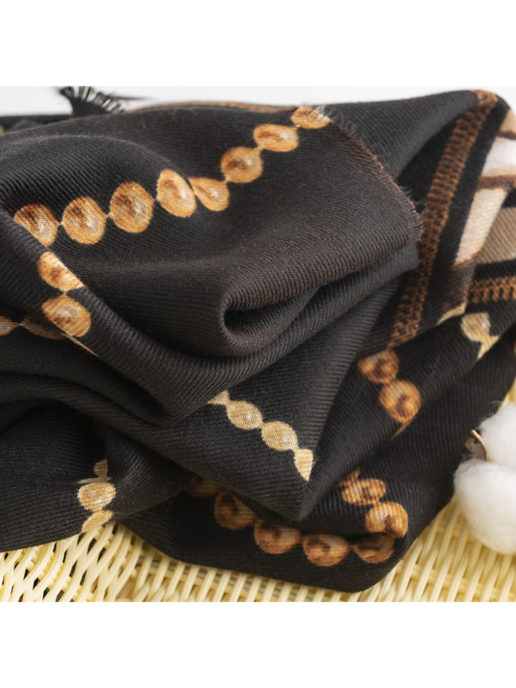 Close-up of Black scarf folds with gold-tone bead-chain motifs and fine textile texture