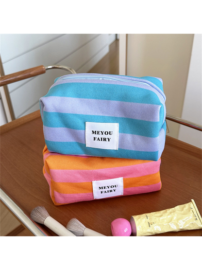 Turquoise striped makeup bag stacked above an Orange striped bag