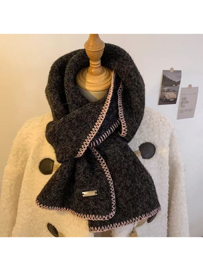 Black scarf looped around a mannequin with pale pink stitched edges