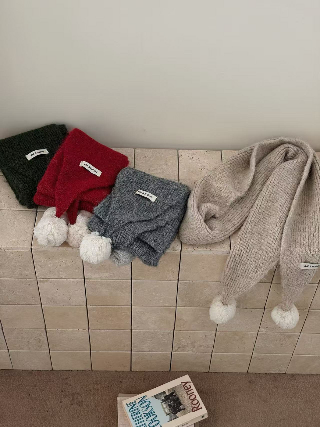 Beige scarf draped beside folded Green, Red and Gray scarves