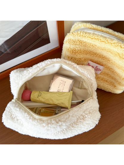 Open Ivory cosmetic pouch showing light-colored lining and styled cosmetics, with a partially visible Yellow pouch behind